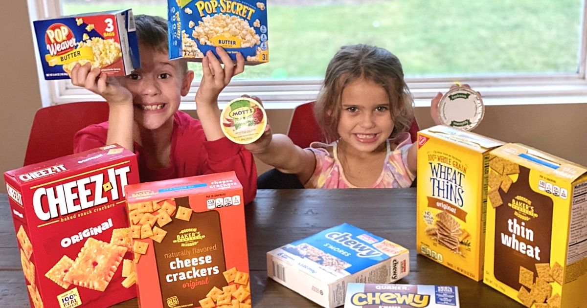 Two kids sitting at a table with various snacks