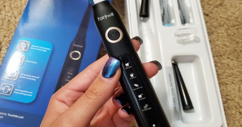 woman holding up a black electric toothbrush