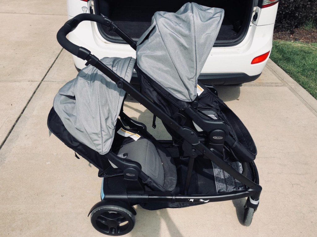 black and gray double stroller in front of white van