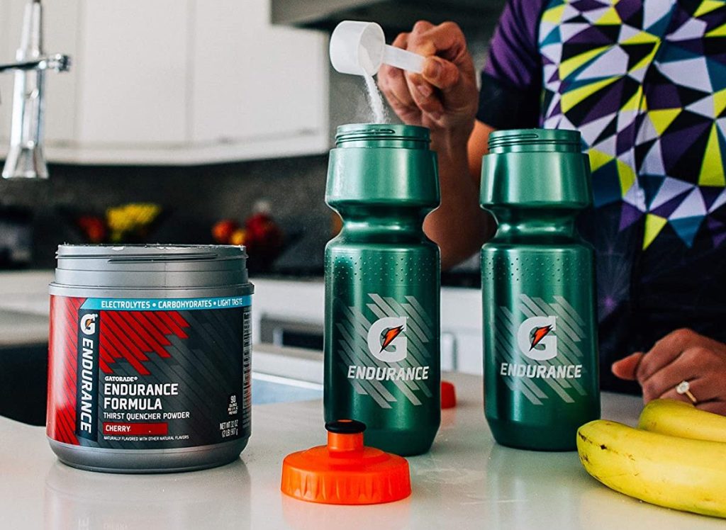 person pouring Gatorade powder in a water bottle