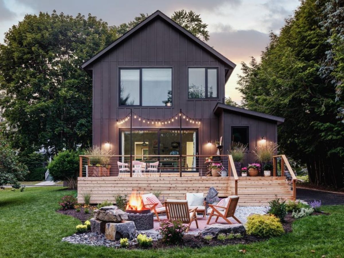 back of brown oasis home with deck and fire pit area