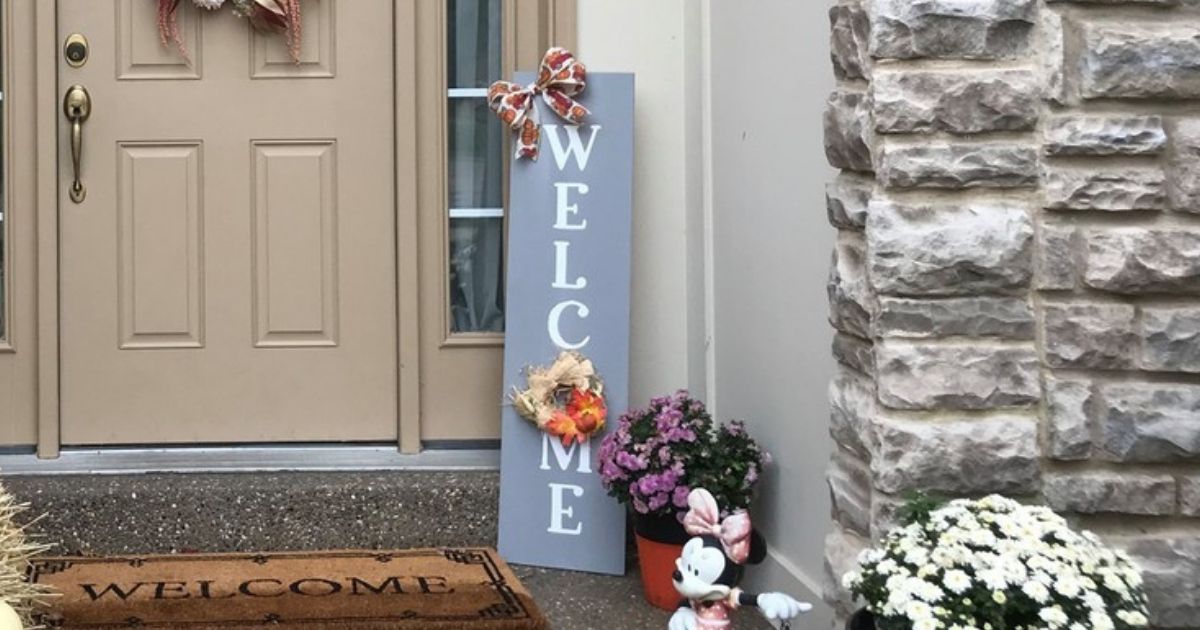 Gray and white WELCOME sign with bows and wreath decor on front porch