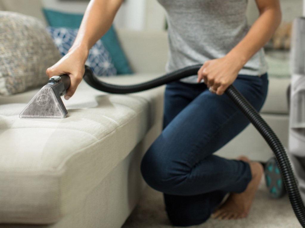 woman using vacuum attachment on couch
