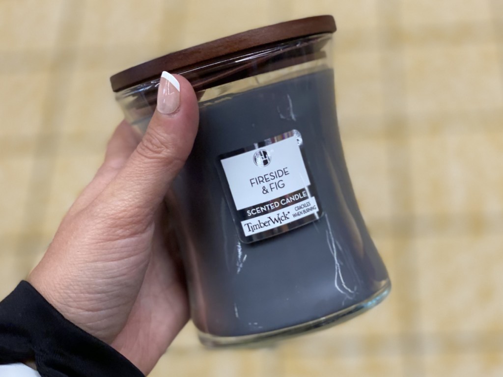 manicured hand holding fireside and fig scented candle