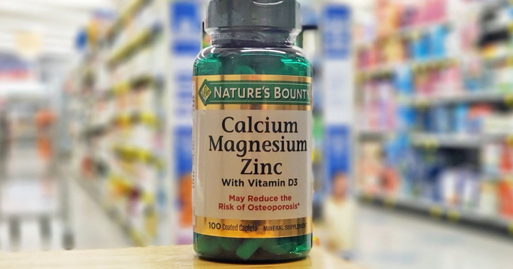 green bottle of Nature's Bounty calcium, magnesium, and znic supplement on wood table at store