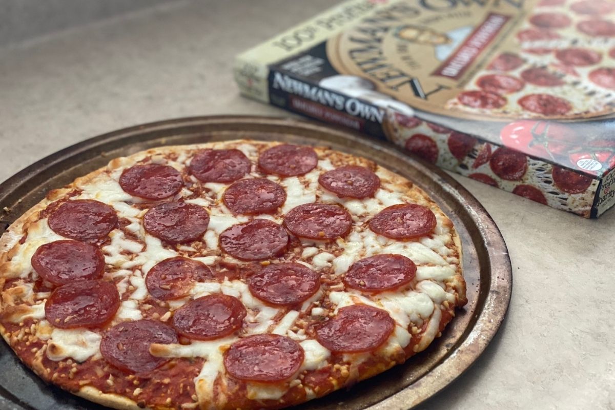 A Newman's Own pizza next to the box on a counter