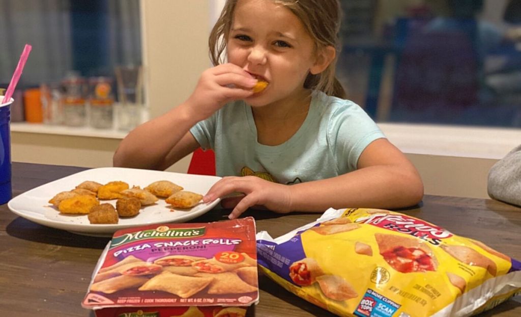 A little girl eating pizza rolls at a table