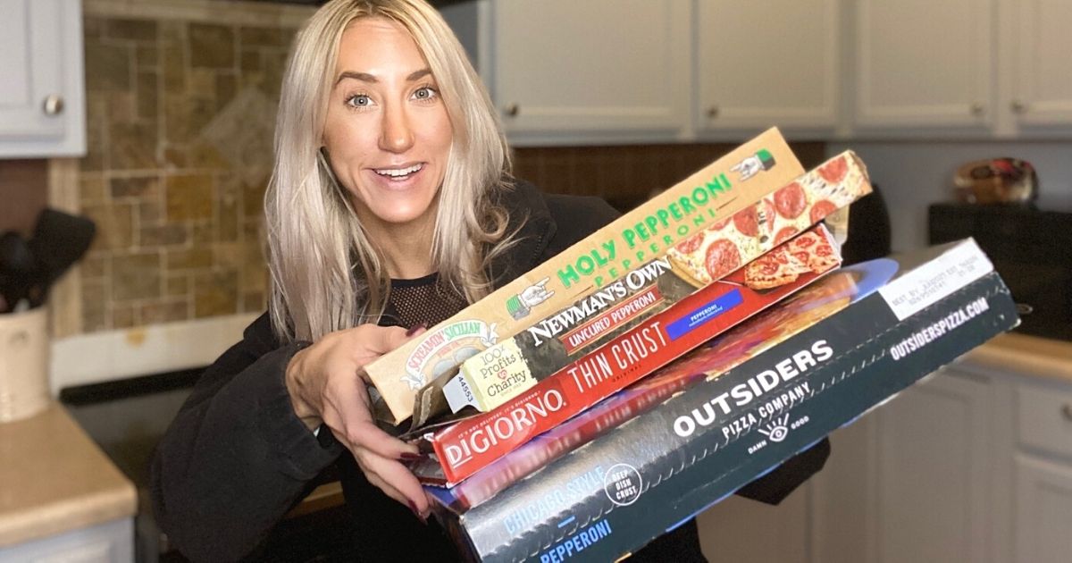 A woman holding boxes of frozen pizza in a kitchen for the best pepperoni pizza taste test