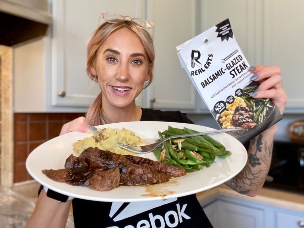 woman holding a plate with steak and potatoes