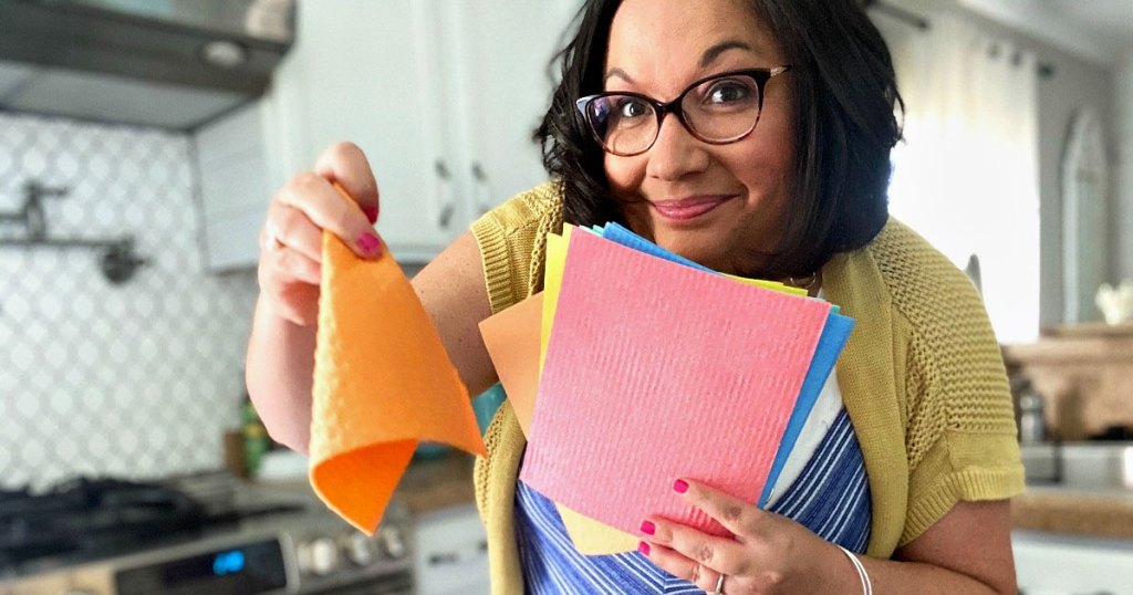 woman with black hair holding up multi-colored swedish dish cloths