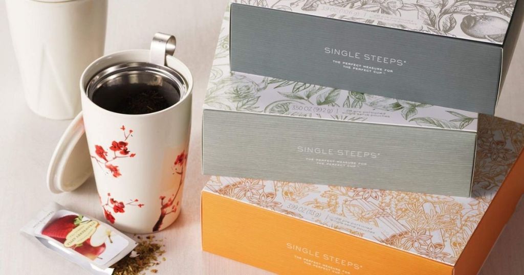 three tea forte gift sets next to a mug with tea in it