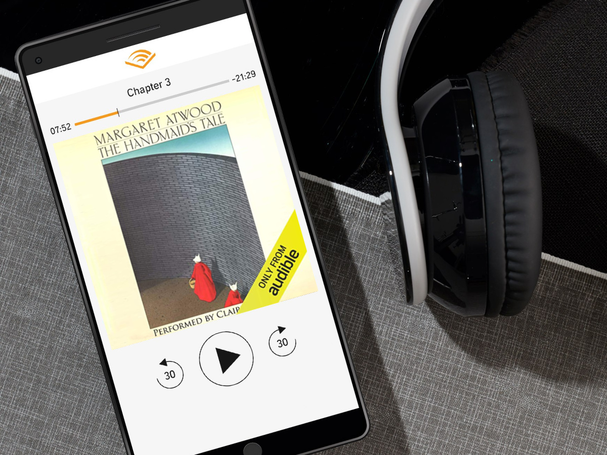 phone playing audiobook with headphones next to it - Amazon digital gifts and online gifts