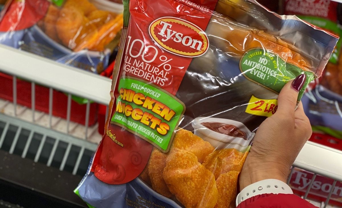 A hand holding a bag of Tyson chicken nuggets at the store