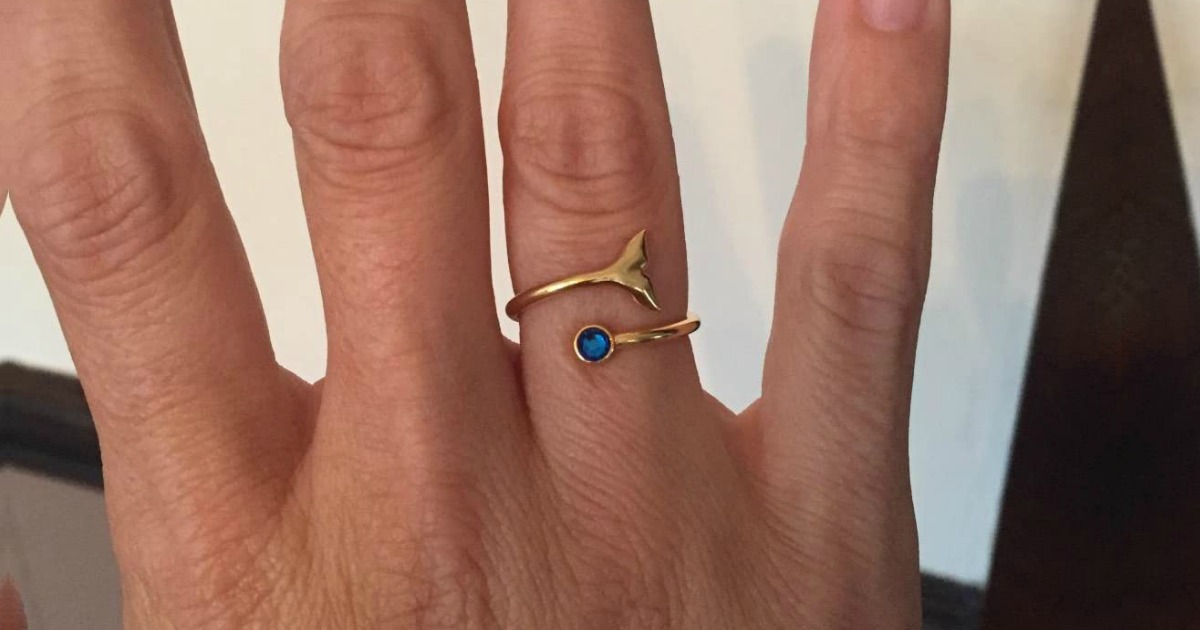 gold ring with a blue stone on a finger