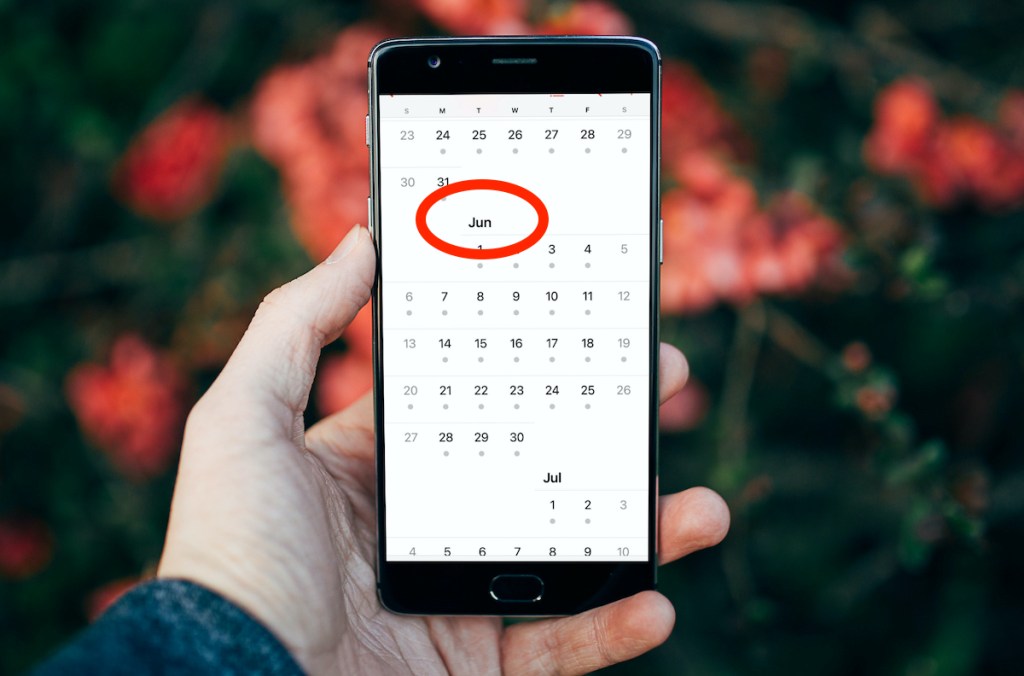 hand holding phone with June calendar on screen