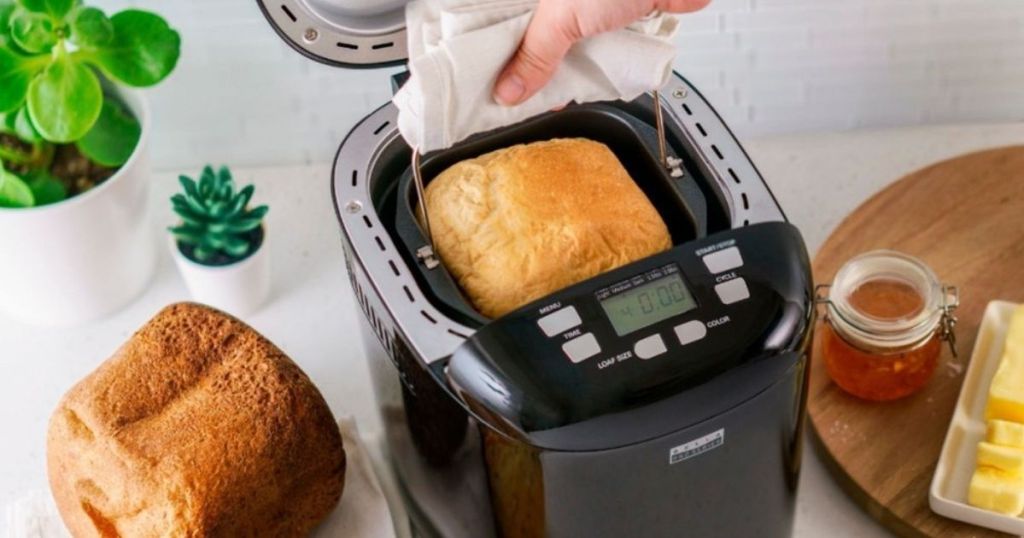 hand taking loaf of bread out of bread maker
