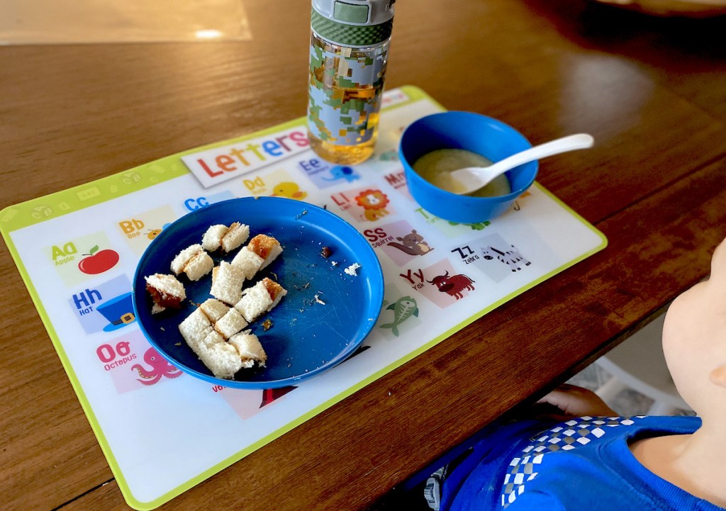 kids letter placemat with blue dishes and food on top on wood table