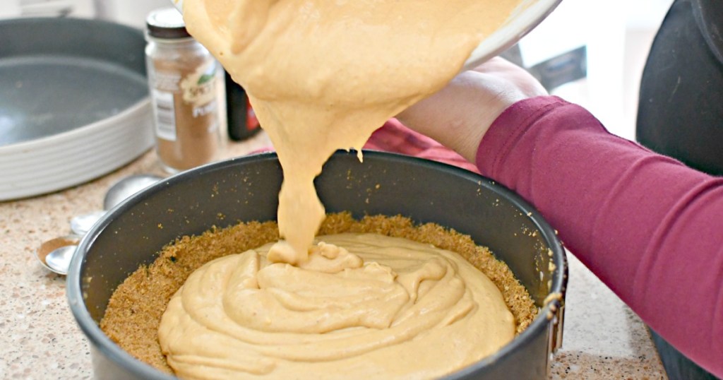 pouring pumpkin cheesecake filling into pan