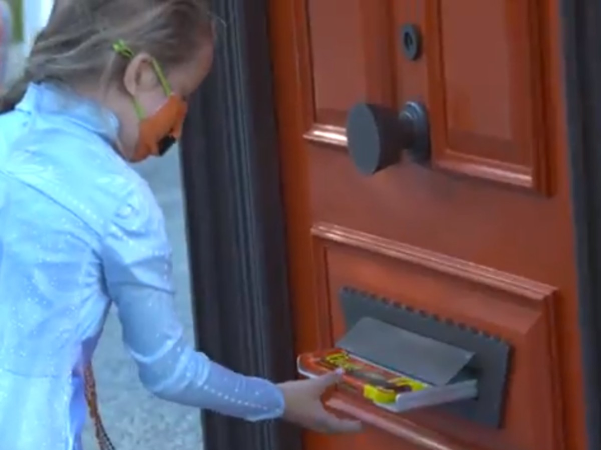 girl getting candy from mail slot on door