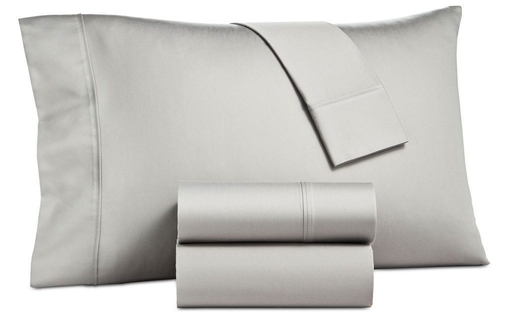 grey sateen pillowcase on a pillow with two folded sheets in front of it