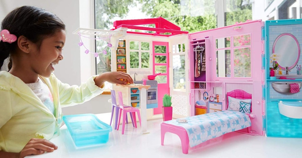 little girl playing with barbie dollhouse set