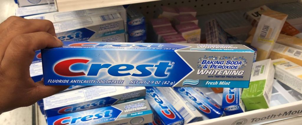 hand holding a tube of Crest toothpaste