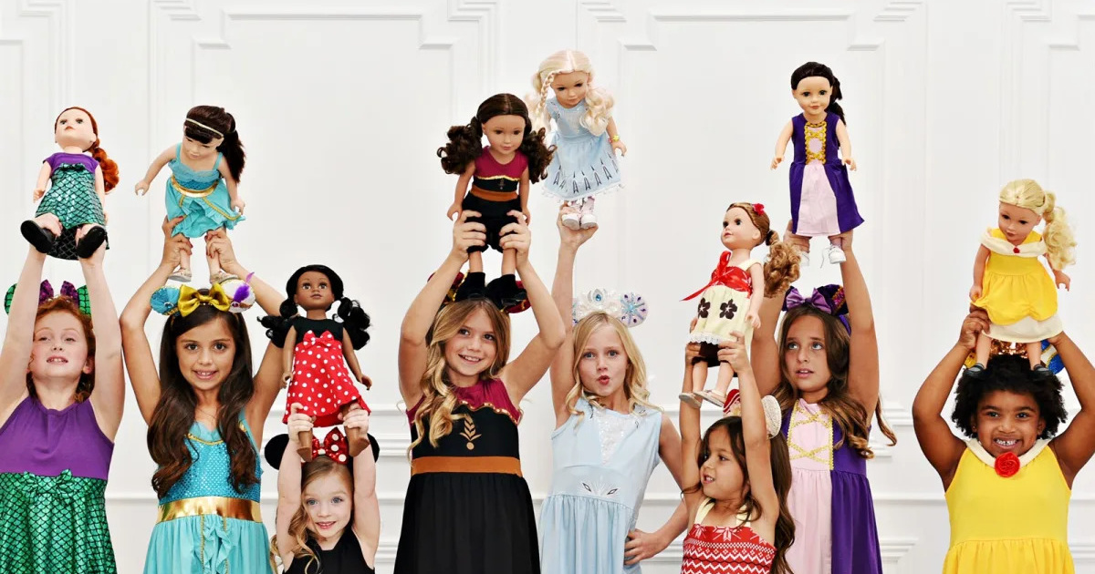 group of girls in princess dresses holding dolls with matching dresses