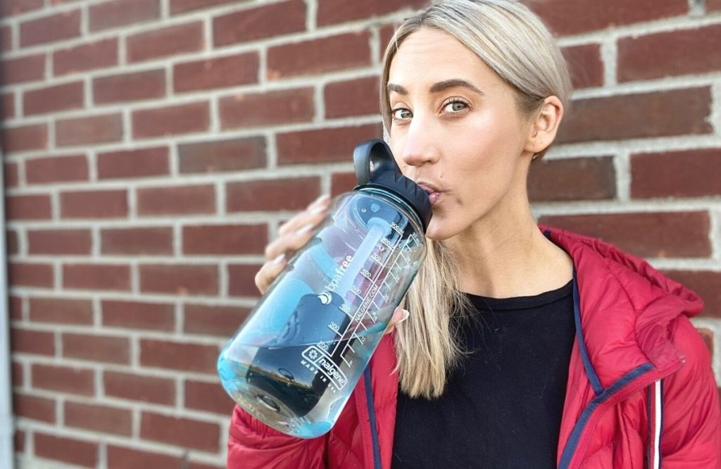 A woman drinking water from a Nalgene water bottle