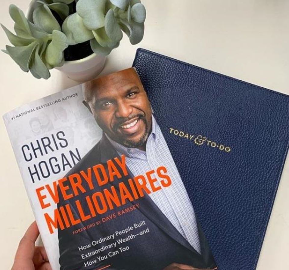 hand holding two books by a plant