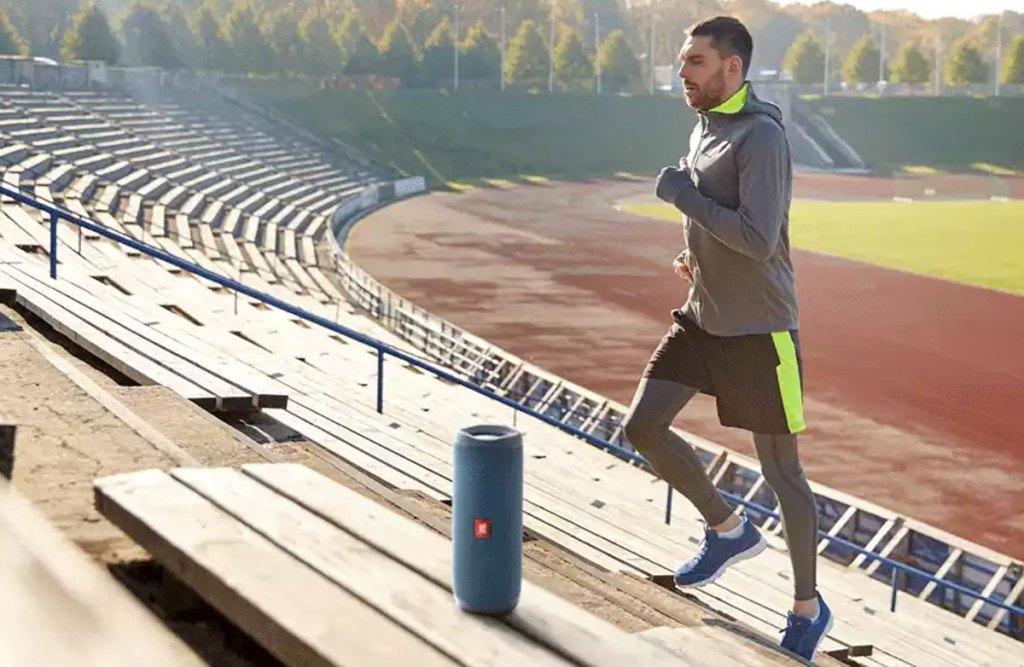 man running up bleachers with blue JBL wireless speaker near him