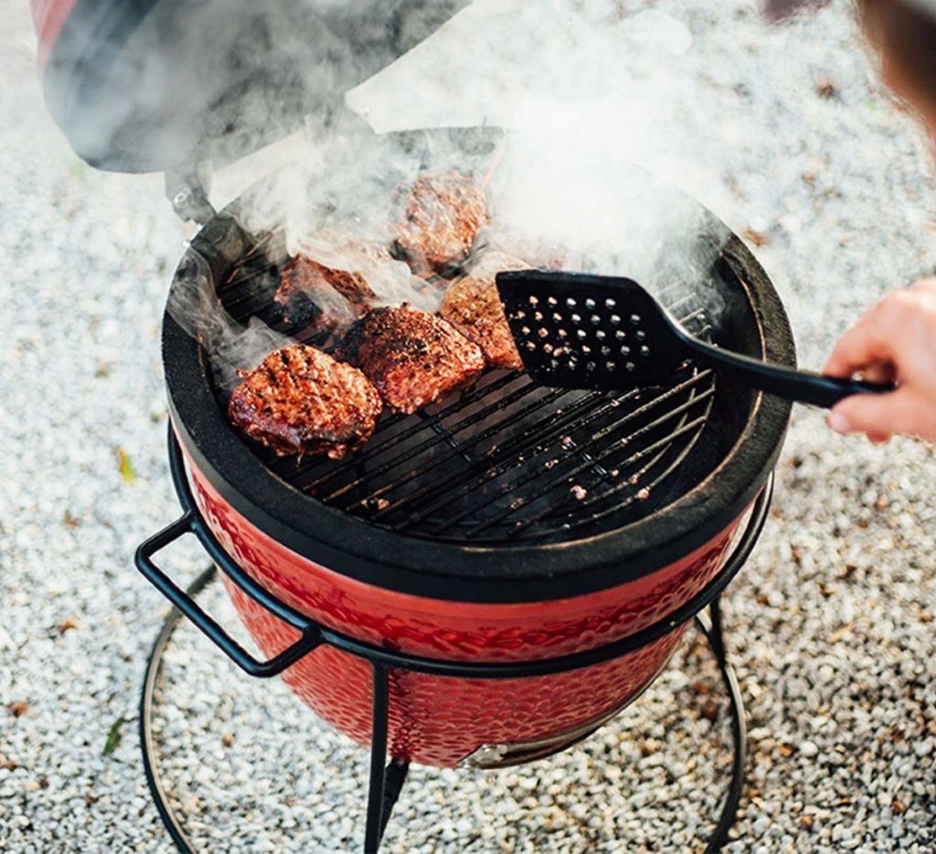 person grill burgers on a small red round grill