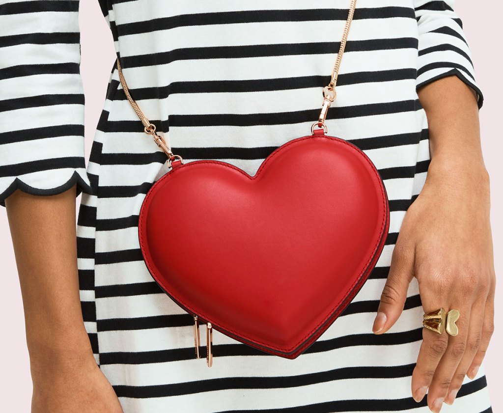 woman in black and white striped dress wearing a red heart shaped crossbody with gold chain strap