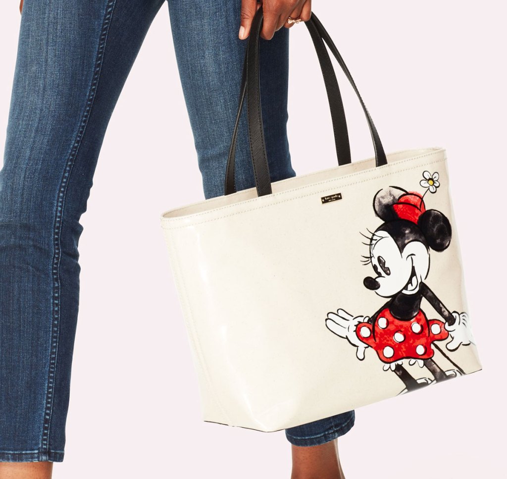 woman wearing skinny jeans and holding white minnie mouse tote bag in her hand