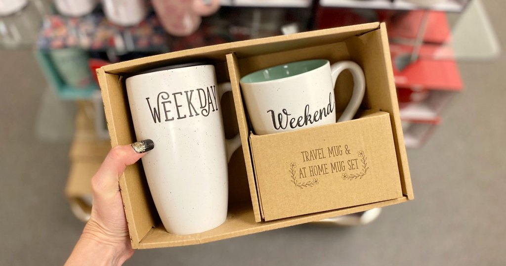 woman holding up boxed coffee mug set with large mug that says "weekday" and smaller mug that says "weekend"