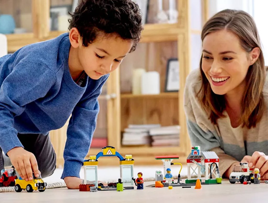 boy and mom playing with a lego city car set on the floor