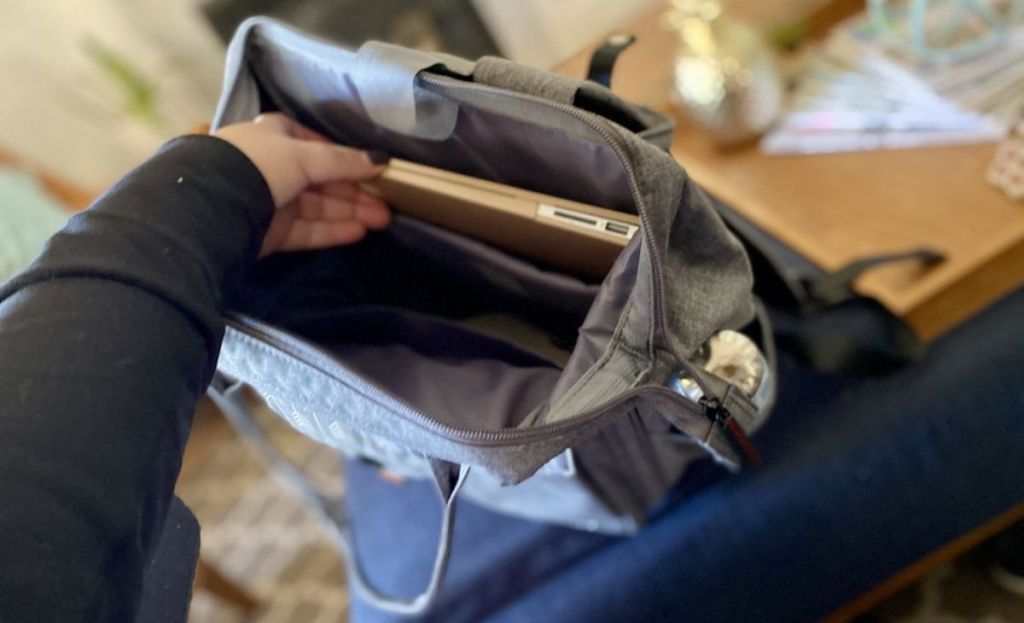 A hand placing a laptop in a backpack