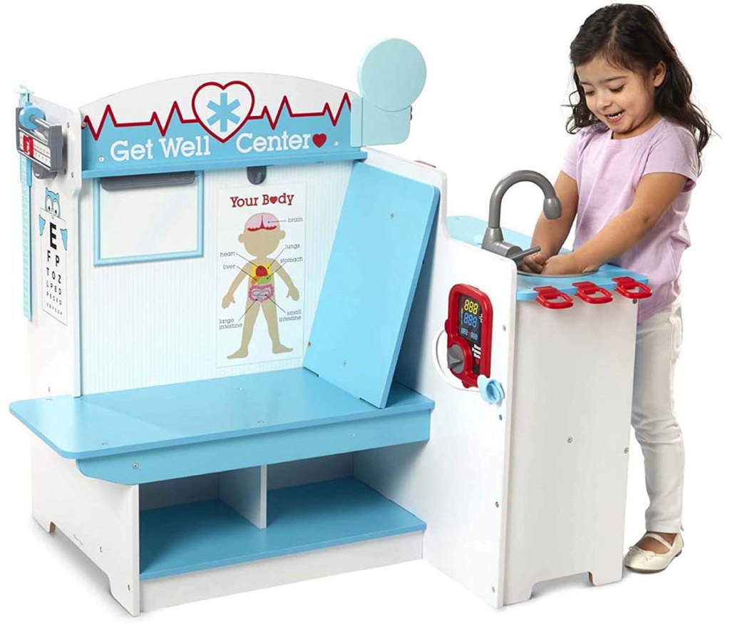 girl washing hands in the sink of a wooden doctor's office playset
