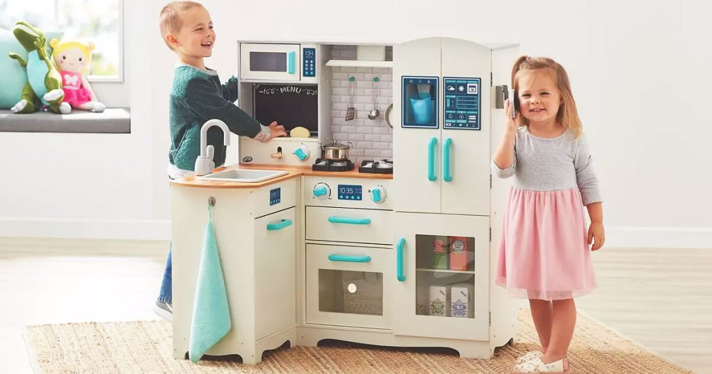 boy and girl playing with an L-shaped wooden kitchen set in a playroom