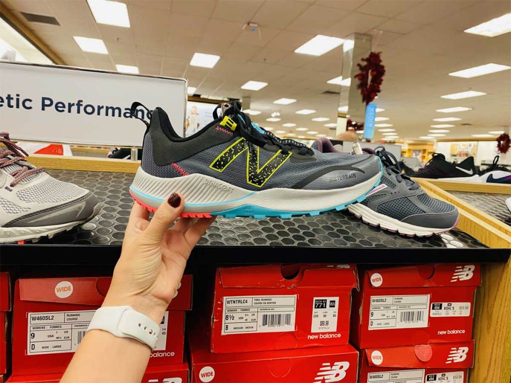 woman holding up a pair of running shoes in store