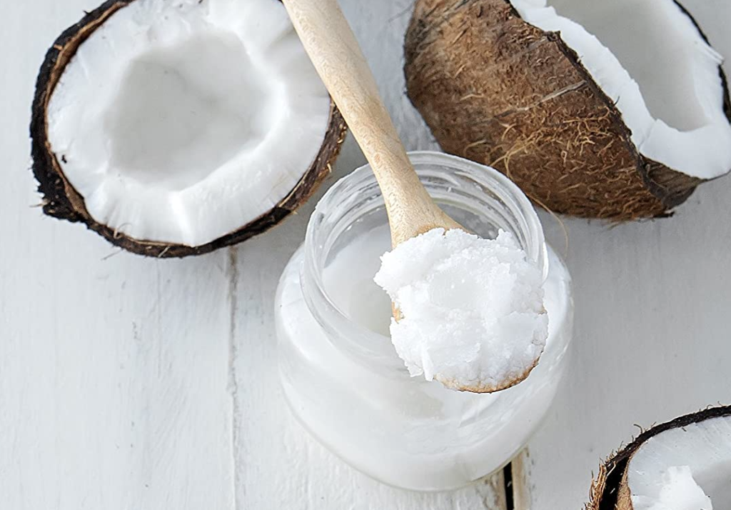 spoon of coconut oil with coconuts next to it