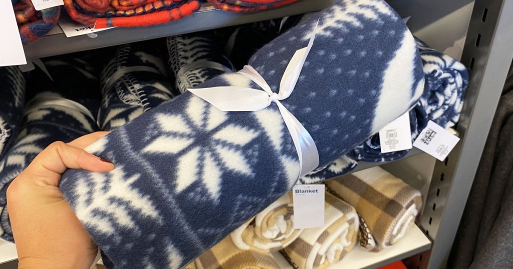 person holding up rolled blue and white printed fleece blanket