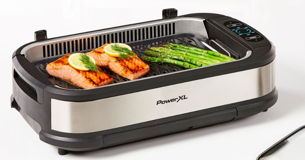 stainless steel and black powerxl indoor grill with two pieces of salmon and asparagus on grilling surface