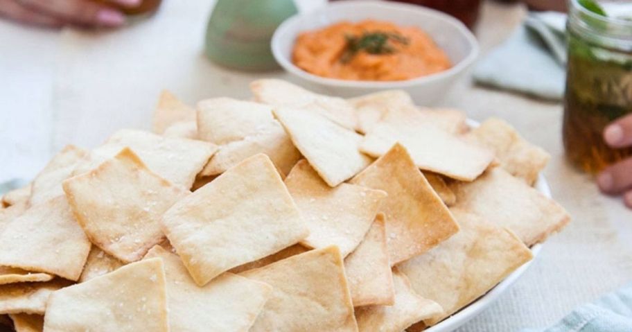 Stacys simply naked pita chips in a basket next to a dip