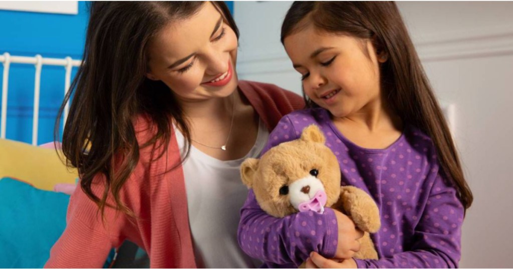 little girl holding a little live teddy bear next to a woman 