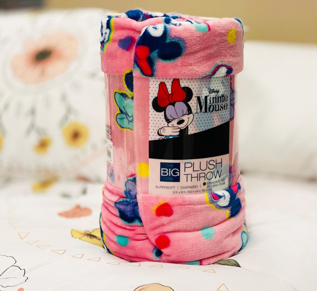 rolled up pink minnie mouse print throw blanket sitting on a bed