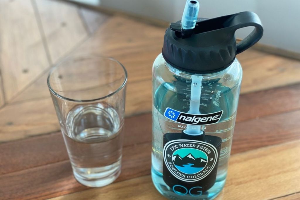 A water bottle next to a glass of water on a counter