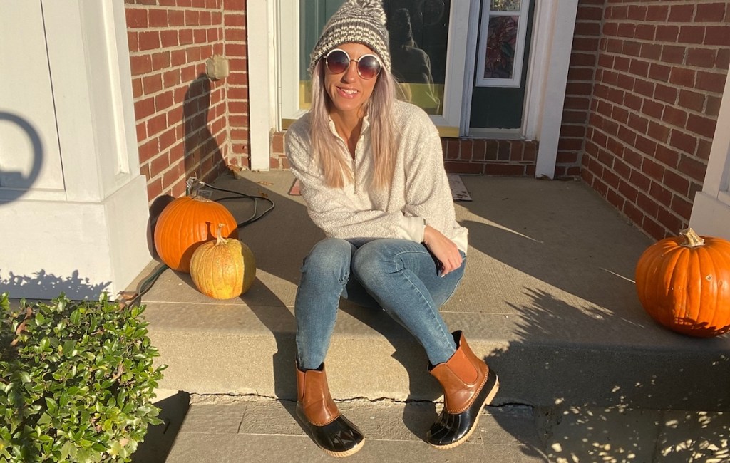 woman sitting on porch with pumpkins 