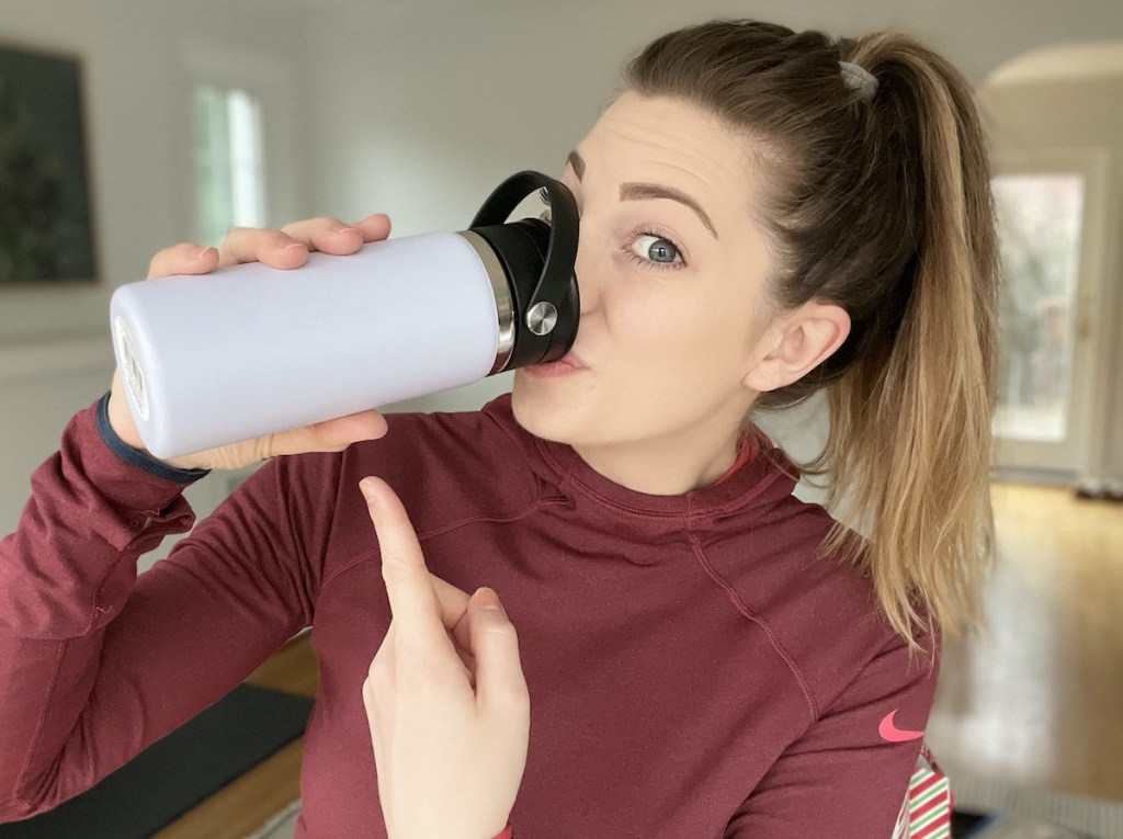woman holding travel coffee mug drinking from lid