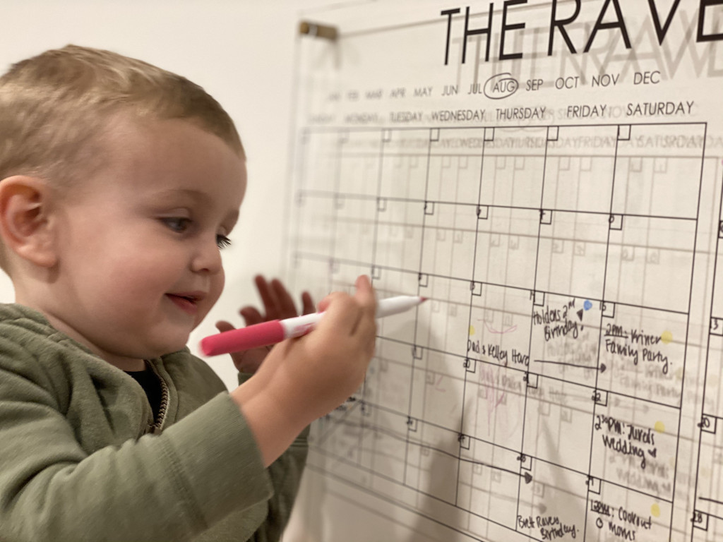 little boy writing on acrylic calendar