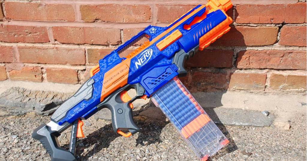 nerf gun on a gravel sidewalk next to a brick wall